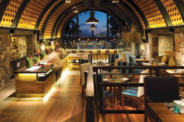 Innenansicht des Outrigger Mauritius Beach Resorts Restaurant mit Holzboden und Steinwänden.