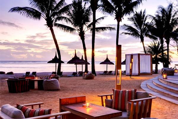 Loungebereich am Strand des Outrigger Mauritius Beach Resort mit Möbeln und Palmen im Hintergrund.