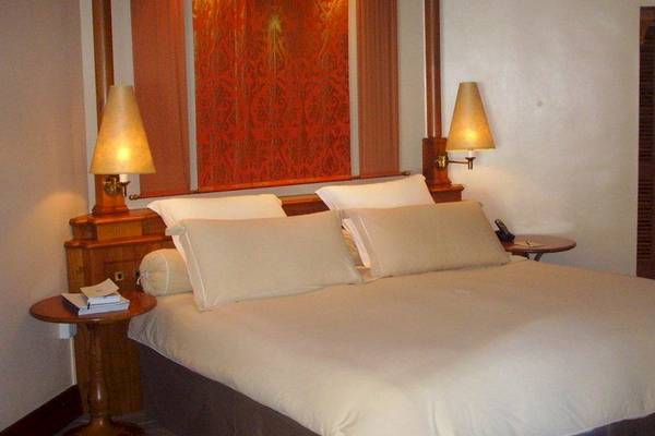 Bett im Hotelzimmer des Outrigger Mauritius Beach Resort mit weißen Laken und Kissen.
