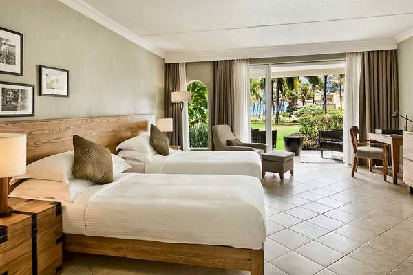 Doppelzimmer im Outrigger Mauritius Beach Resort mit zwei Betten, Blick auf den Garten und Meer.