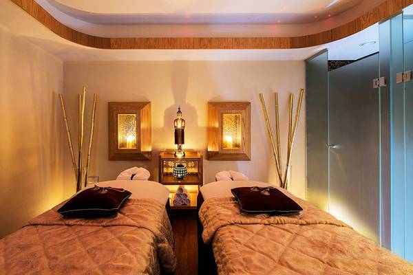 Massage-Behandlungsraum im Athena Royal Beach Hotel mit zwei Betten und Buddha-Statue.