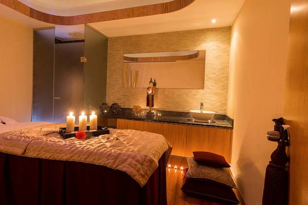 Spa-Behandlungsraum im Athena Royal Beach Hotel mit Kerzen und einem Buddha-Standbild.