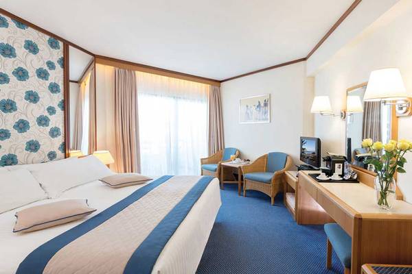 Zimmer im Athena Royal Beach Hotel mit Bett, Fernseher und Schreibtisch