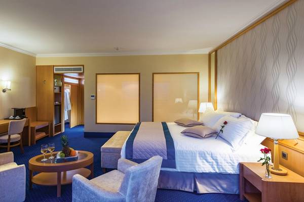 Zimmer im Athena Royal Beach Hotel mit einem Bett und Sitzgelegenheiten.