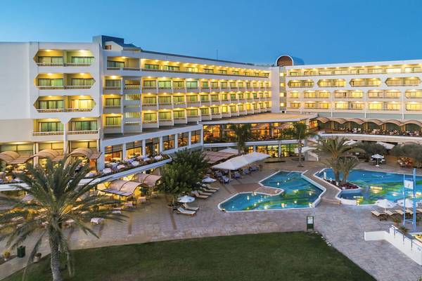 Außenansicht des Athena Royal Beach Hotel mit Swimmingpool und Loungebereichen.