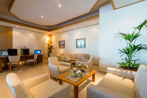 Lobby-Bereich im Athena Royal Beach Hotel mit Möbeln, Pflanzen und Monitoren.