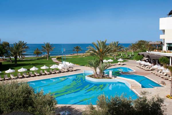 Oberirdischer Pool des Athena Royal Beach Hotels mit Sonnenliegen und Palmen