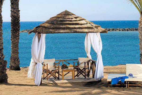 Sitzplatz im Athena Royal Beach Hotel mit Blick auf das Meer und weißen Vorhängen.