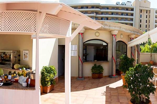 Terrasse des Princess Inspire Tenerife Hotels mit Tischen, Stühlen und Gästen unter weißen Sonnenschirmen.