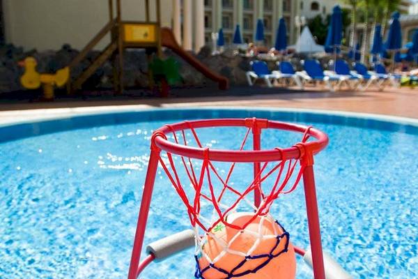 Schwimmbad im Princess Inspire Tenerife Hotel mit einem roten Basketballkorb und einer Rutsche im Hintergrund.