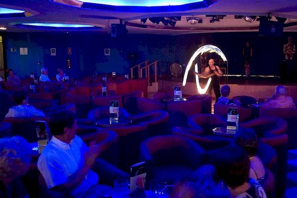 Eine Nachtclubszene im Princess Inspire Tenerife Hotel mit einer Frau, die eine Feuershow auf der Bühne vorführt.
