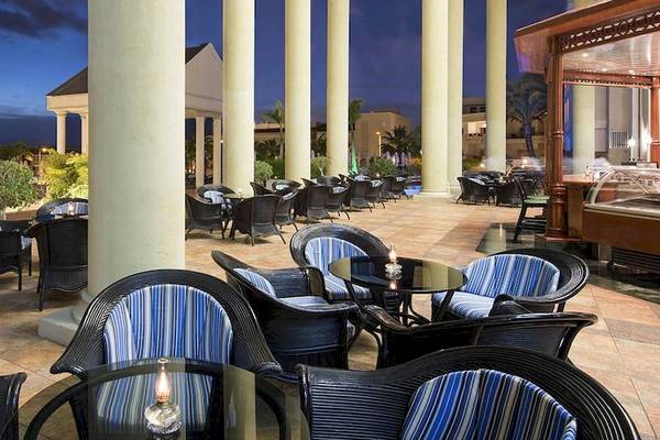 Außenbereich des Princess Inspire Tenerife Restaurants mit blauen und weißen Stühlen und Tischen, umgeben von Pflanzen und Säulen.