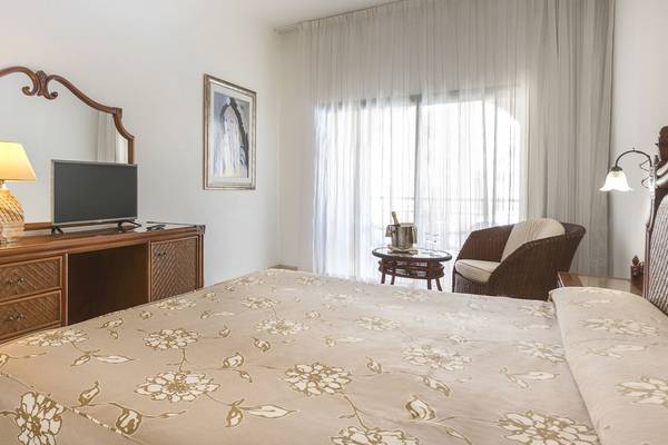 Schlafzimmer im Princess Inspire Tenerife Hotel mit Bett, Fernseher, Spiegel, und Tisch mit Weinflasche.