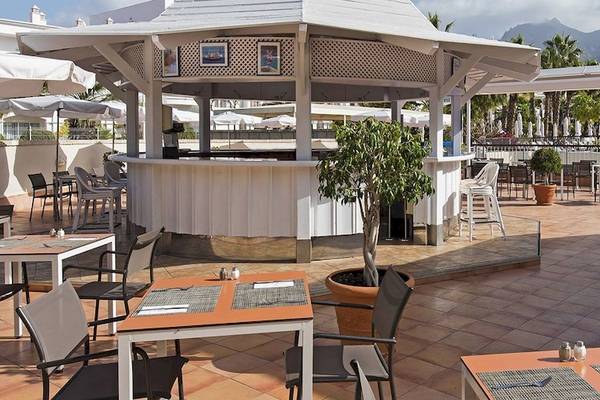 Außenterrasse des Princess Inspire Tenerife Hotels mit Tischen, Stühlen und einer Bar.