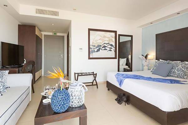Ein modernes Hotelzimmer im Royal Blue Resort mit Fernseher, Sofa, Tisch und Bett.