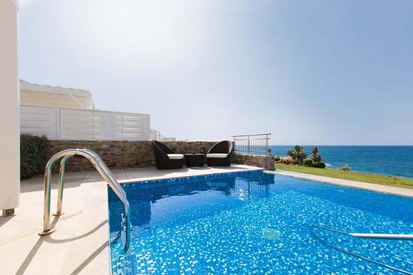 Der Pool mit Aussicht auf das Meer im Royal Blue Resort mit zwei Stühlen und einem Tisch.