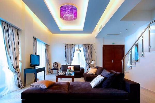 Wohnzimmer im Royal Blue Resort mit modernen Möbeln, Deckenbeleuchtung und einer großen Couch.