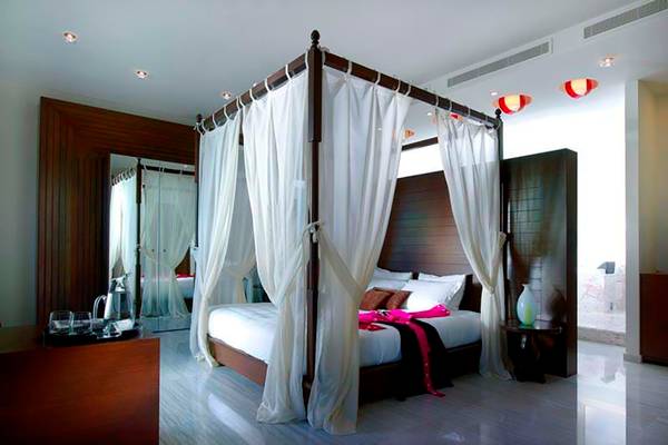 Schlafzimmer im Royal Blue Resort mit Himmelbett, weißen Vorhängen und luxuriösem Interieur.
