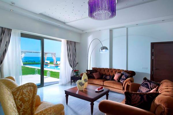 Wohnzimmer im Royal Blue Resort mit einem großen Sofa, einem Tisch und einem Lampenschirm.