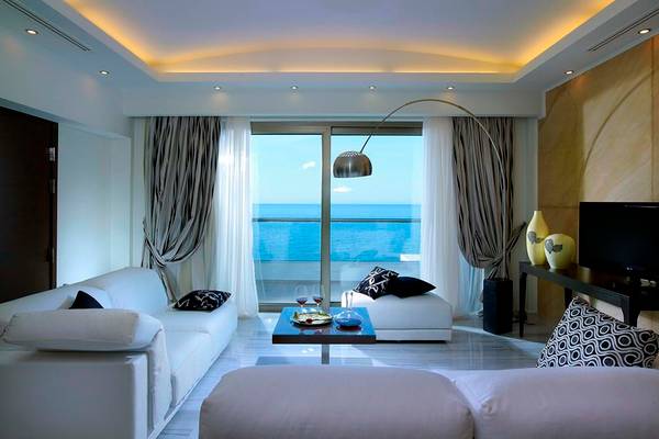 Wohnzimmer im Royal Blue Resort mit Meerblick, modernen Möbeln und großen Fenstern.