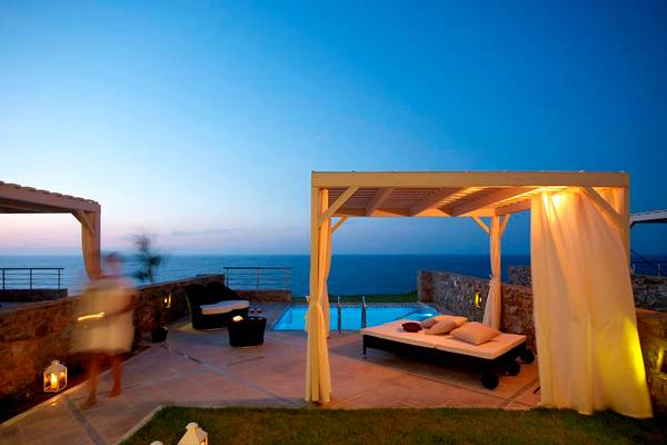 Terrasse des Royal Blue Resorts bei Abend mit Pool, Loungemöbeln und Meerblick