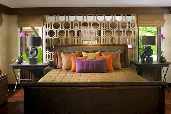 Schlafzimmer im Rayavadee Hotel mit einem großen Bett, gemusterter Wand und Nachttischen.