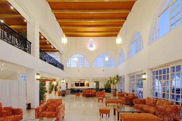 Lobby des Platanista Hotels mit großen Fenstern, Holzdecken und orangefarbenen Möbeln.