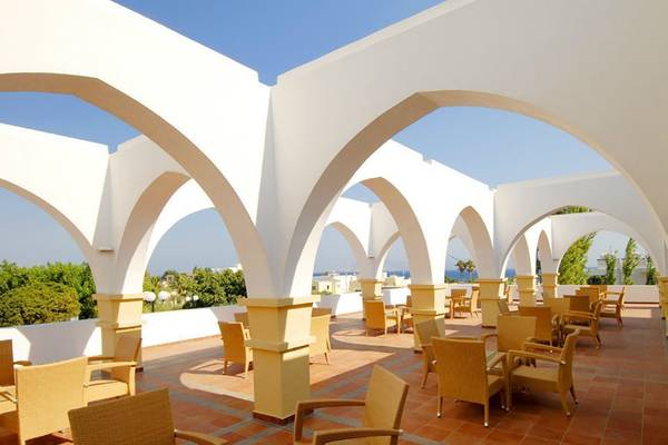 Terrasse des Platanista Hotels mit gelben Stühlen und Tischen unter Bögen.