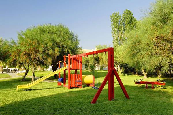 Kinderspielplatz im Platanista Hotel mit gelber Rutsche und roten Schaukeln.