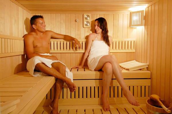 Ein Paar genießt Zeit in der Sauna des Platanista Hotels, beide tragen Handtücher.