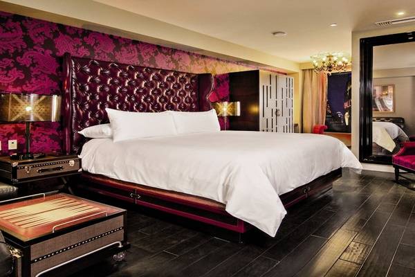 Schlafzimmer im Cromwell Las Vegas Hotel mit einem großen Bett, rotem Kopfteil und gemusterten Wänden.