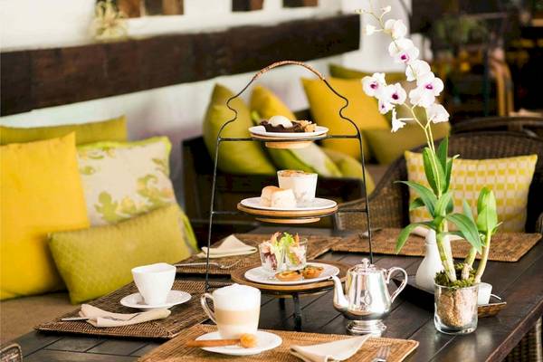 Nachmittagstee-Arrangement im Rayavadee Hotel mit gelben Kissen und weißen Orchideen.