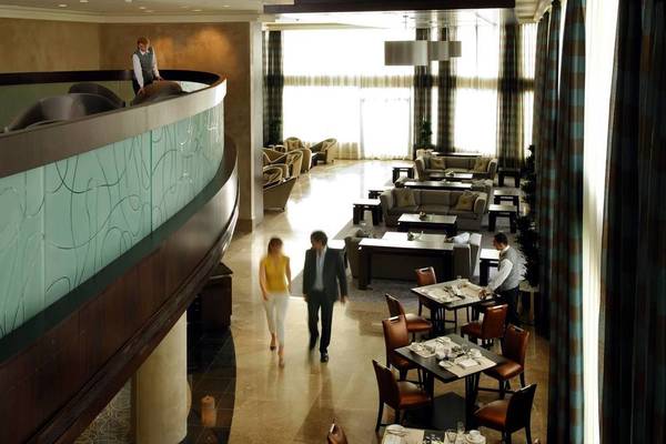 Foyer eines Hotels mit Loungebereich und Bedienung an Tischen.
