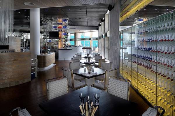 Innenansicht des Restaurants im Intercontinental Abu Dhabi mit Tischen, Stühlen und einer Bar.