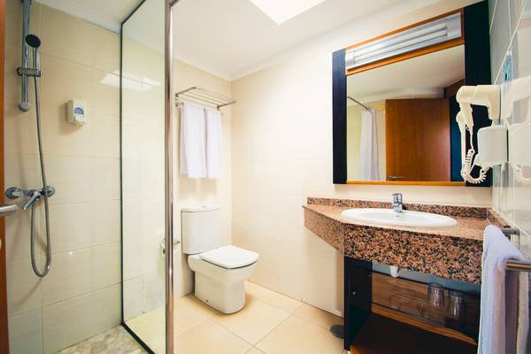 Badezimmer im HL Miraflor Suites mit Dusche, Toilette, Waschbecken und Spiegel.