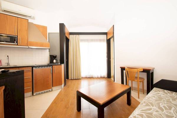 Innenansicht eines Zimmers im HL Miraflor Suites Hotel mit Küche, Tisch und Bett.