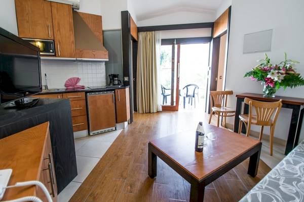 Wohnbereich im HL Miraflor Suites mit Tisch, Stühlen und Fernseher.