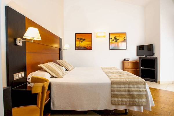 Schlafzimmer im HL Miraflor Suites mit Bett, Nachttischen und Fernseher.