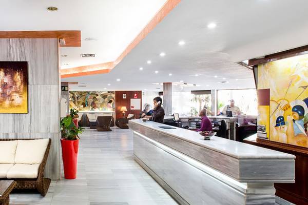 Empfangsbereich des Alexandre Hotel Troya mit Rezeption, Couch und Kunstwerken.