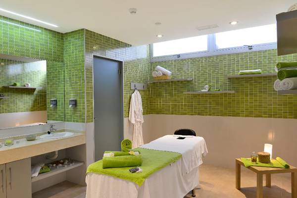 Massage-Behandlungsraum im Alexandre Hotel Troya mit grünen Fliesen und einer Liege.