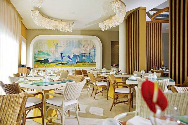 Innenbereich des Restaurants im Secrets Royal Beach Punta Cana mit bunter Wandmalerei.
