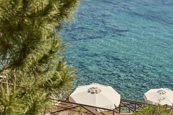 Candia Park Village Terrasse mit zwei weißen Sonnenschirmen und Blick auf das Meer.