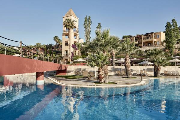 Pool im Candia Park Village Hotel mit Palmen und Sonnenschirmen im Hintergrund.