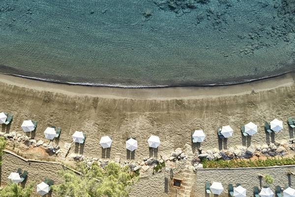 Luftaufnahme von Strand und weißen Sonnenschirmen im Candia Park Village Hotel.