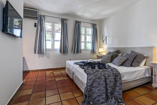 Schlafzimmer im Candia Park Village Hotel mit einem großen Bett, Nachttischen und Wandleuchten.