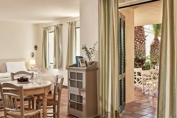 Innenansicht eines Zimmers im Candia Park Village Hotel mit einem Bett, Tisch und einem offenen Balkon