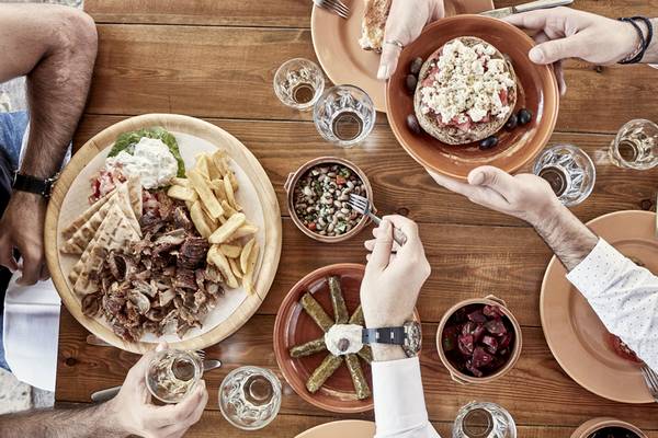 Gruppe isst im Candia Park Village mit verschiedenen Gerichten wie Gyros, Pommes, Hummus und Salat.