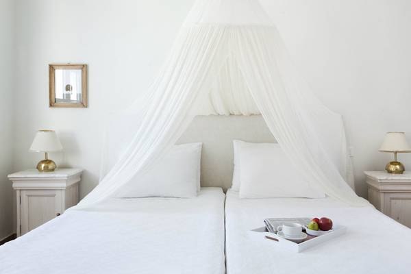 Zwei Betten im Candia Park Village mit weißen Laken, Kissen und einer durchsichtigen Himmelbett-Bettwäsche.