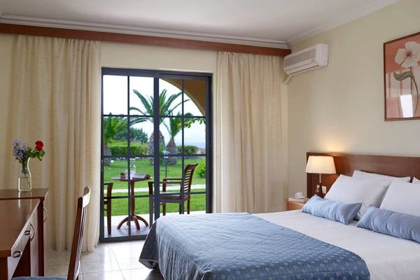 Schlafzimmer im Porto Bello Beach Hotel mit Bett, Tisch und Stuhl vor einer Terrasse