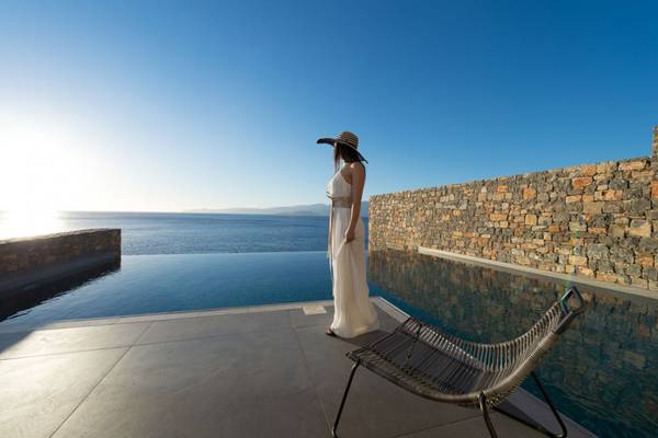 Frau auf der Terrasse des Elounda Village Resorts mit Blick auf das Meer.
